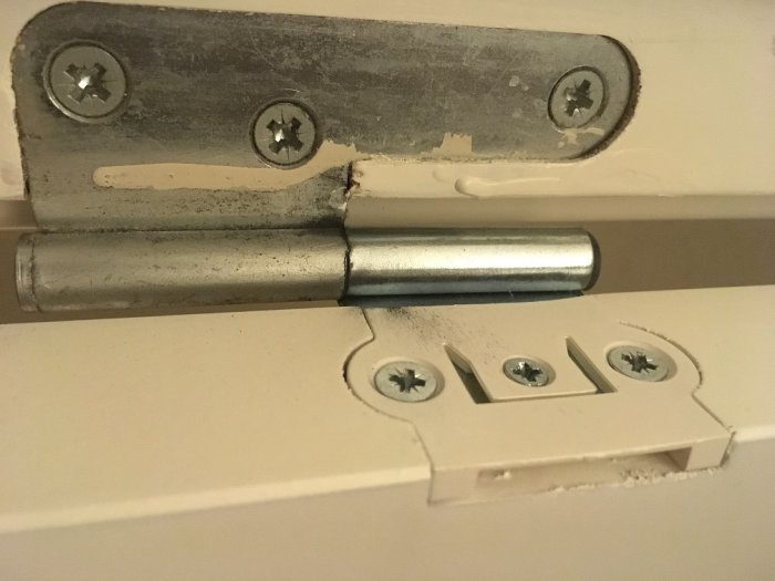 Närbild av en dörrgångjärn montering på vit dörrkarm utan synlig adapter.