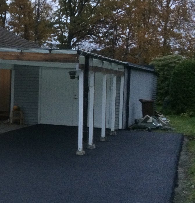 Stuprör på en carport som leder regnvatten ned mot asfalterad yta.