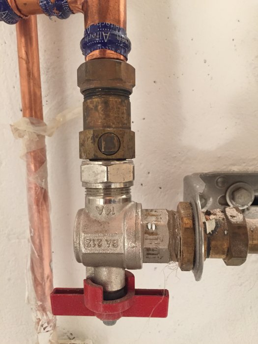 Kopparrör med en klämringsmutter och efterföljande metallventil med röd spak och osäker tillverkare, möjligtvis en form av ventil.