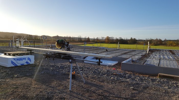 Byggplats redo för gjutning med armeringsjärn och träformar under en klar himmel.