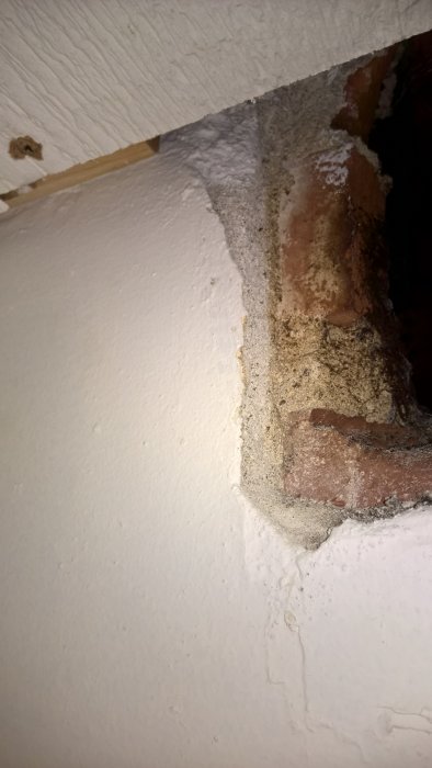 Delvis målad och putsad murstock med synliga tegelstenar och en rå yta, planerat för väggtegelklädsel.