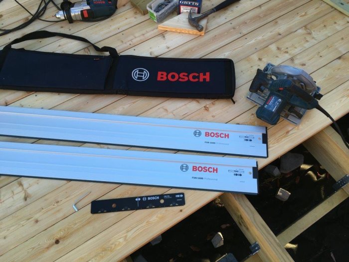 Två Bosch FSN1600 styrskenor och skarvbeslag på en träaltan, med förpackningar, sänksåg och en bärväska.