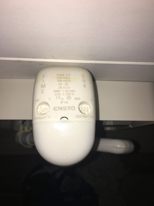 Närbild av en takarmatur med en rörelsevakt från Ensto märkt med olika inställningsparametrar för lux och tid.