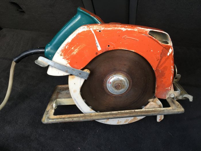 En gammal tung cirkelsåg med en 210mm klinga på en bilens säte, utan märkesbeteckning.