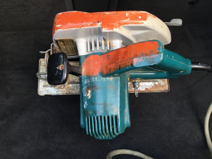 Gammal cirkelsåg med 210mm klinga, sliten med orange och turkos färg utan synlig märkning.