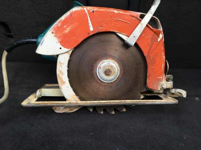 En gammal sliten cirkelsåg med en 210mm klinga och metallbas, utan synlig märkesbeteckning.