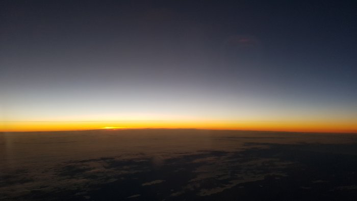 Soluppgång ovanför molntäcket sett från flygplansfönster på morgonen.