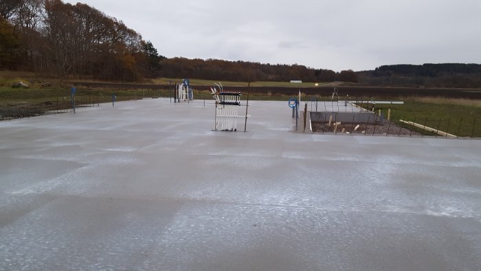 Nyutgjuten betongplatta för byggprojekt med avspärrning och skog i bakgrunden.