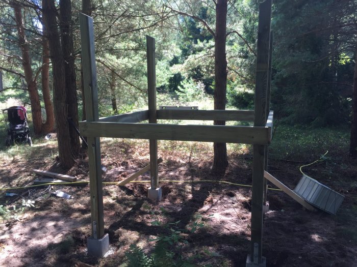 Grundstommen till en träkoja under konstruktion i en skoglig miljö.