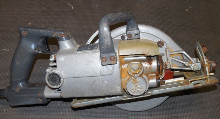 Kapsåg med vinkelväxel bakom klingan, handtag ovanför och bakom motorn, skymt av klingskydd och gul tub.