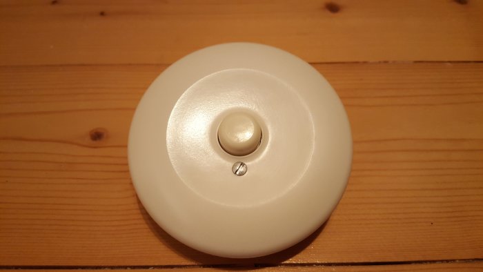 Vit brandvarnare monterad på ett träunderlag.