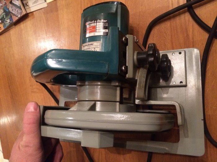 Gammal Black & Decker cirkelsåg från 70-talet, grön och silverfärgad, hålls i handen.