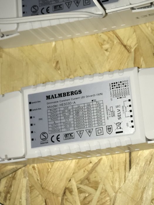LED-drivdon från Malmbergs, Model: HE5030-A, med specifikationer och märkning på en träbakgrund.