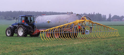 Traktor med gödselspridare på ett fält, redo att sprida olika sorters gödsel.