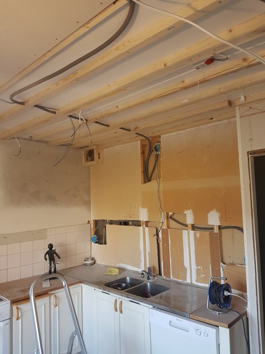 Nyinstallerade gipsskivor på taket i en köksrenovering med spackel och målarutrustning synligt.