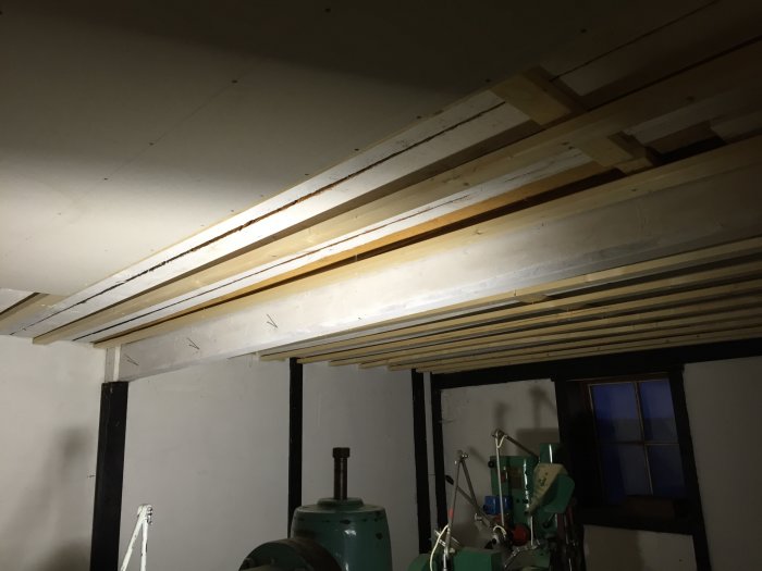 Innertak i en lada under renovering med nyinstallerade gipsskivor och justerade reglar synliga.