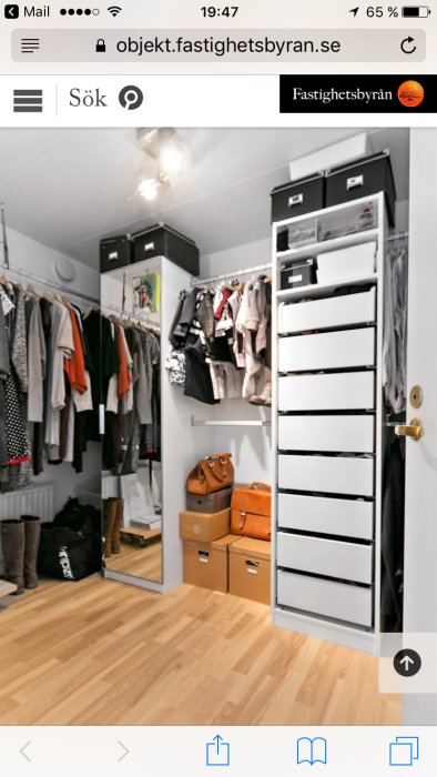 Organiserad garderob med klädhängare, öppna hyllor och lådor monterade på väggen i ett sovrum.