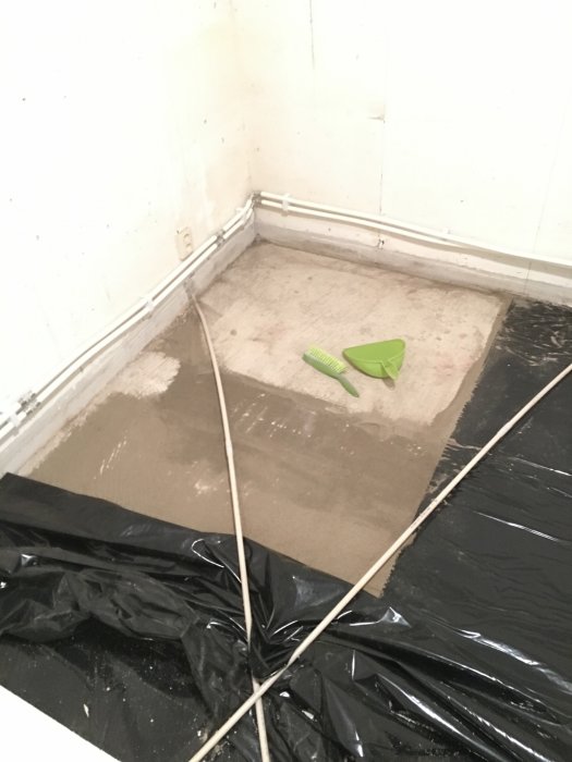 Fuktig sand och avtryck efter golvspån på betongplatta i husrenoveringsprojekt.