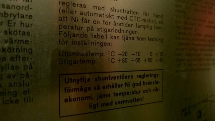 En svagt belyst tabell och text som rekommenderar inställningar för värmesystem för optimal bränsleekonomi och jämn temperatur.