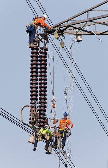 Elektriker som arbetar på en högspänningsstolpe med komplexa installationer för 400 kV ström.