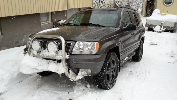 SUV parkerad med snö upp till stötfångaren, reflekterande en snörik dag i Stockholm.