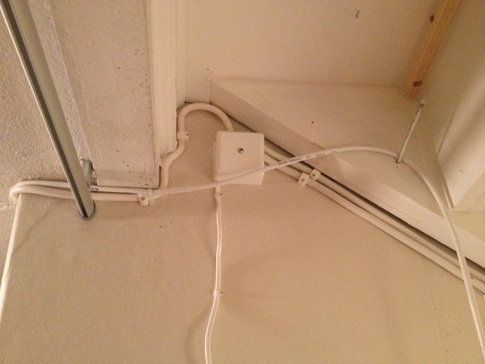 Oorganiserad elinstallation med lampsladd för strömbrytare och synliga kablar längs taket.