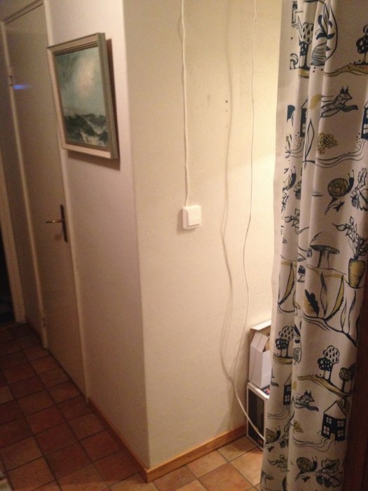 Oegentligt installerad lampsladd som hänger längs väggen och används för strömbrytare i hemmiljö.