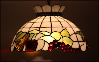 Tiffany-stil, färgglad bordslampa med detaljerad glasmosaik i rött, gult och grönt upplyst inifrån.