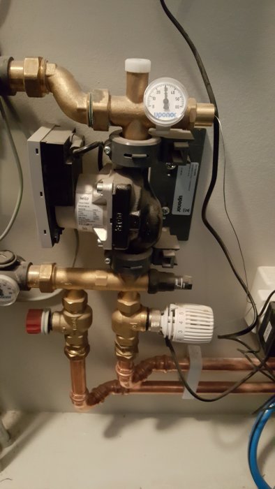 Upponor golvvärmefördelare med manometer, Wilo-cirkulationspump och justerbar vit termostatknopp.