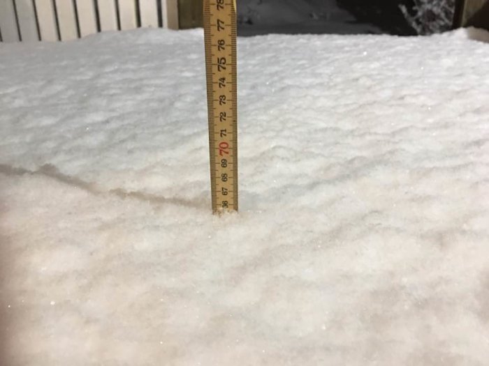 Mätsticka i snö visar djupet, cirka 30 cm, på en yta i Bromma.