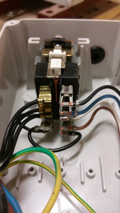 Elektrisk anslutning med flera färgkodade sladdar kopplade till ett nollspänningsskydd.