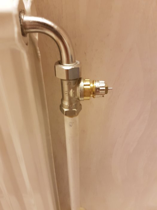 Värmeelement med synligt rör och ett regleringsventil med två reglage, det yttre avlägsnat så att den inre fjädern syns.