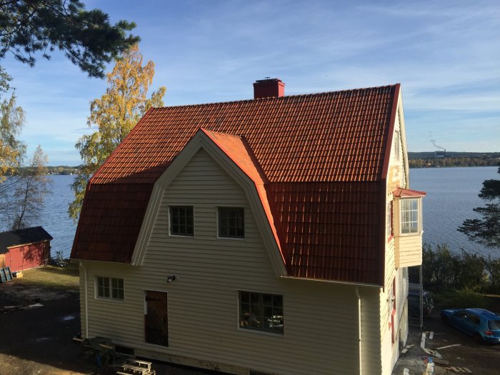 Renoverat hus med nytt tegeltak färdigt för vintern vid sjökanten.