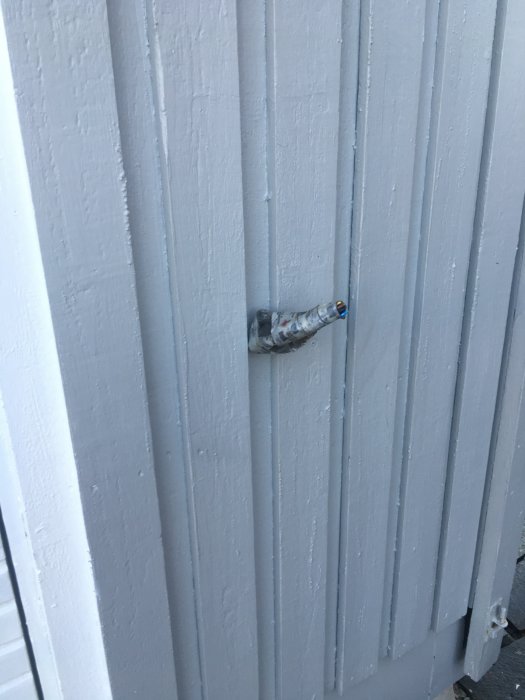 Utskjutande rör med sladdar genom vit panelvägg, verkar oavslutat.