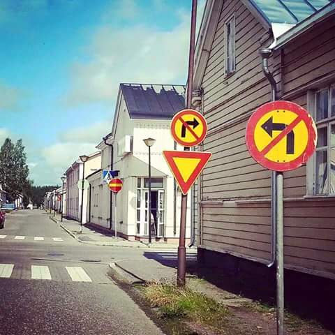 Gata i stadsmiljö med flera trafikskyltar, inklusive stoppförbud och väjningsplikt.