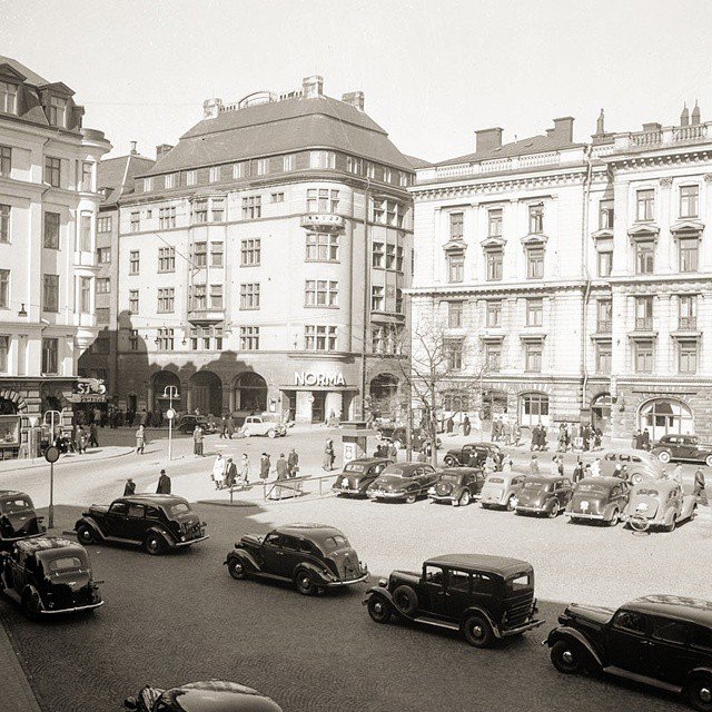 Svartvit bild av historiskt hörn vid Vasagatan och Klarabergsgatan med fordon och gående.