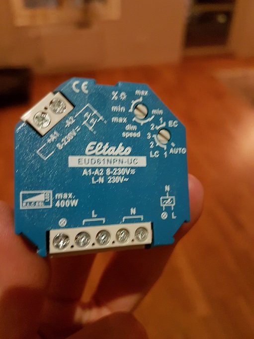 Eltako EUD61NPN-UC dosdimmer hållen i hand framför suddig bakgrund.