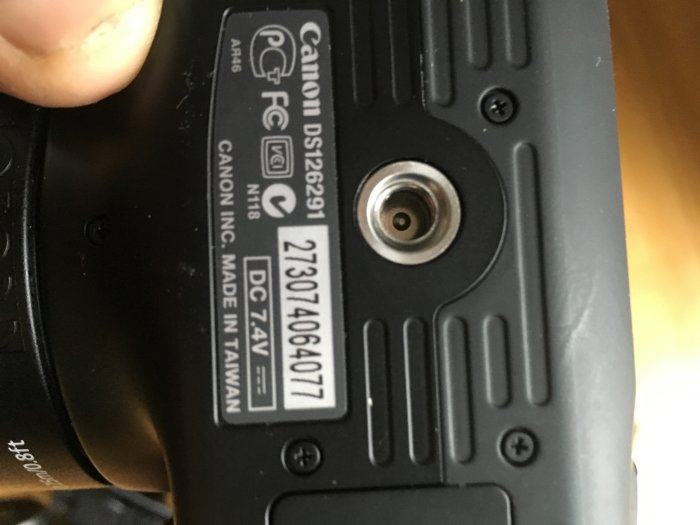 Bild på undersidan av en Canon-kamera som visar modellnummer och tillverkningsinformation.