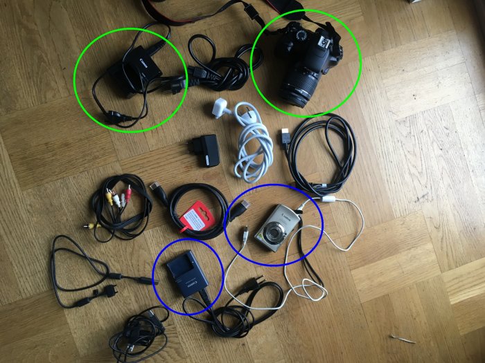 Olika elektronikprylar och kablar på ett golv, markerade med cirklar som kopplar samman kameror med tillhörande laddare.