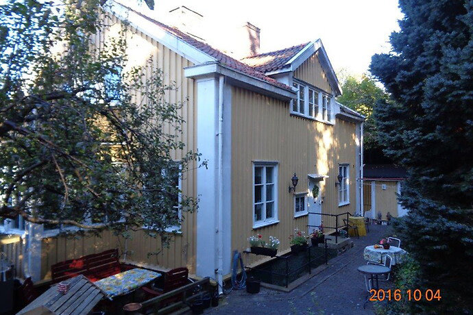 1920-talshus i gult med röda takpannor och terrass, omgivet av grönska på Carlbergsgatan i Göteborg.