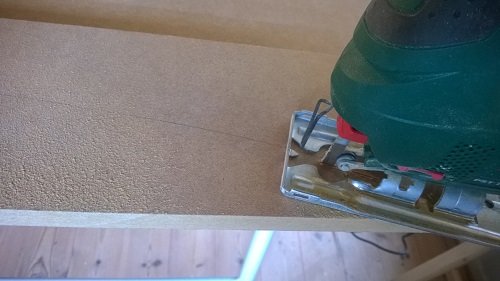 En handöverfräs som används på en MDF-skiva för att formge en bågformad dörrkarm.