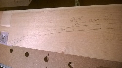 En MDF-skiva med uppritade markeringar för att skapa en mall för karmarnas bågformade överstycken.