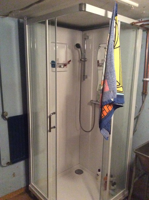 Duschkabin installerad i ett renoveringsprojekt, med handdukar och hygienprodukter inuti.