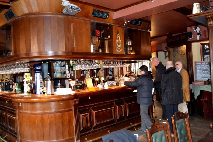 Träbar med detaljerad mallfräsning och kunder som står och beställer, inrett i klassisk stil.