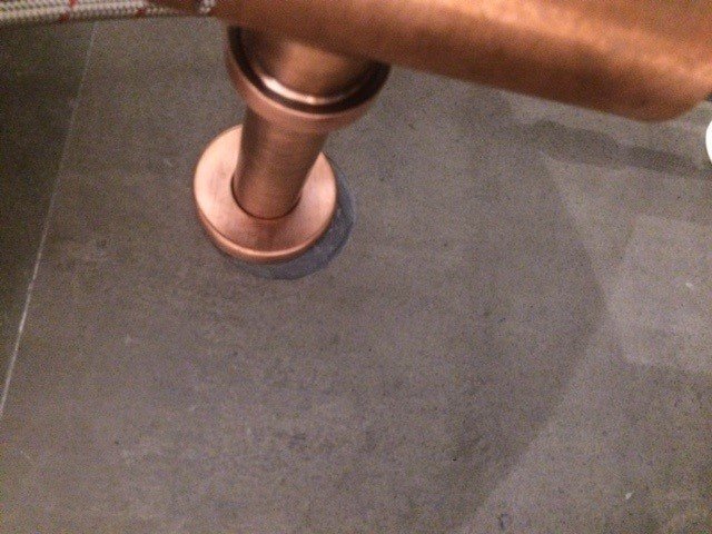 Närbild på röranslutning till vägg, potentiellt avloppsvattenlås under handfat med bristfällig precision.