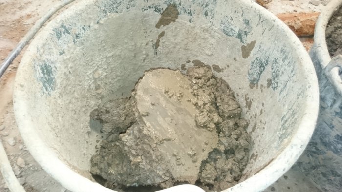 En hink fylld med en blandning av lera och cement som ser ut att ha blivit omrörd eller bearbetad.