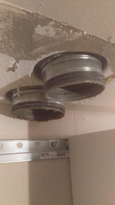 Två flexibla köksventilationsslangar i taket redo för justering i renoveringsprojekt.
