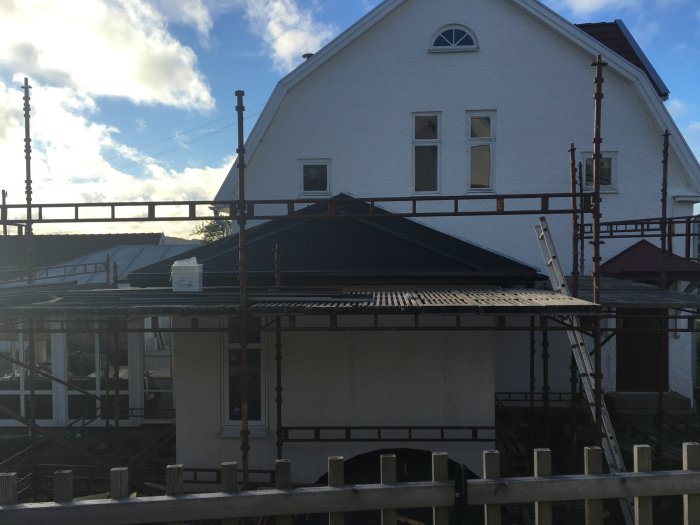 Hus under renovering med byggnadsställningar och pågående tillbyggnadsarbete.