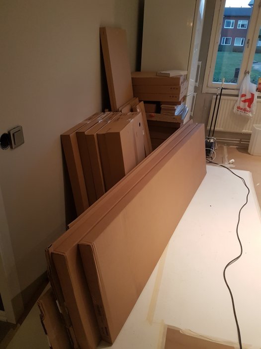 Ouppackade köksstommar och lådor i kartonger som är färdigskruvade och redo för montering i ett rum under renovering.