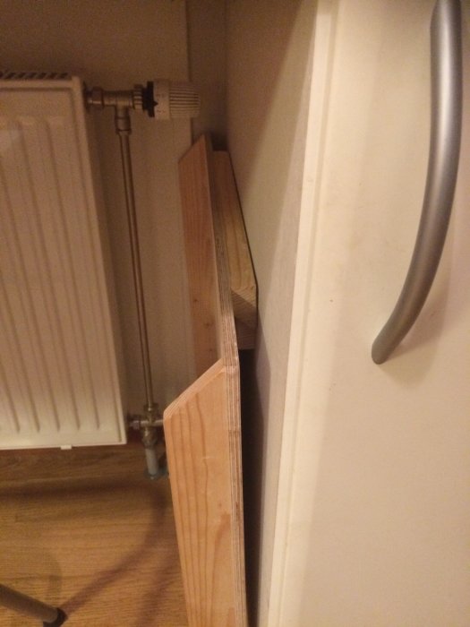 Tre bakbord i björkplywood med olika storlekar står lutade mot en vägg nära en elementradiator.